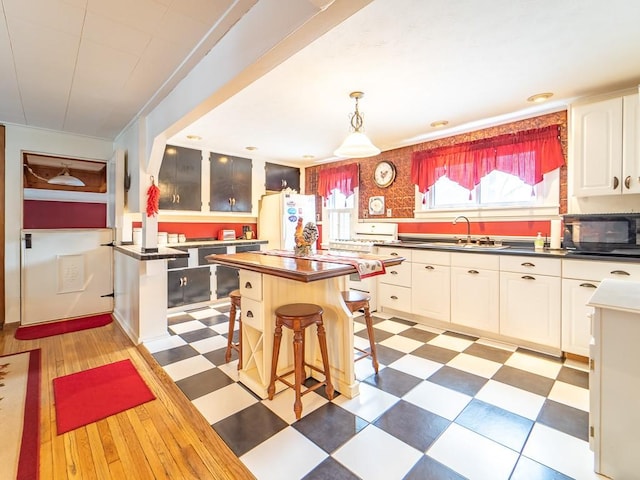 kitchen featuring sink, a center island, white refrigerator, a kitchen breakfast bar, and white cabinets