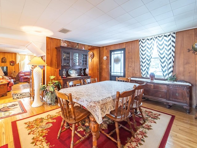 dining space featuring light hardwood / wood-style floors and wood walls