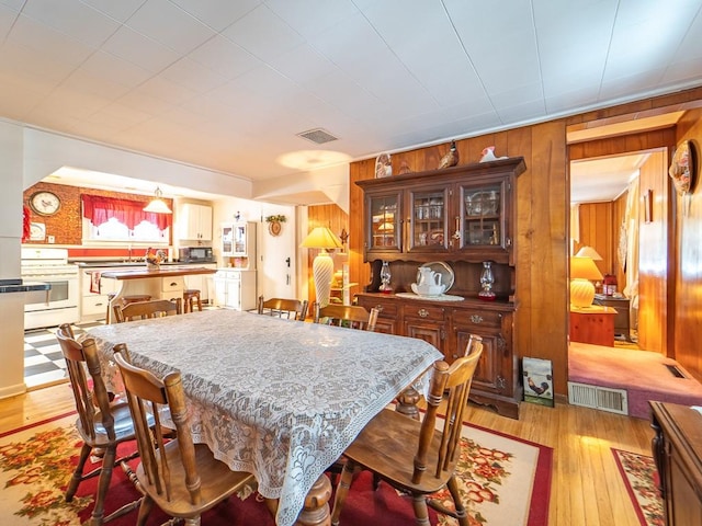 dining space with wood walls and light hardwood / wood-style flooring