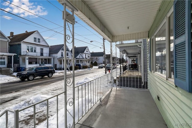 snow covered back of property with a porch