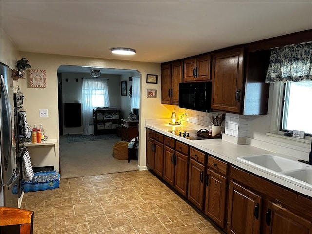 kitchen with dark brown cabinetry, a wealth of natural light, sink, and black appliances