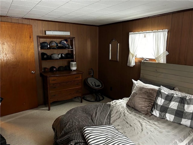 bedroom featuring wooden walls and light carpet