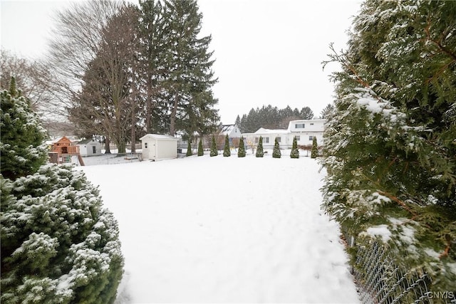 snowy yard featuring a storage shed