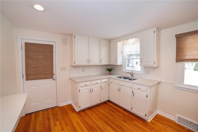 kitchen featuring tasteful backsplash, sink, white cabinets, and light wood-type flooring