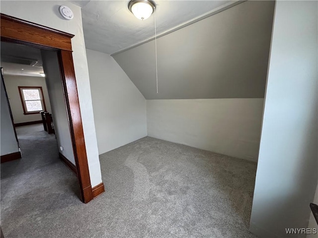 additional living space featuring dark colored carpet and vaulted ceiling