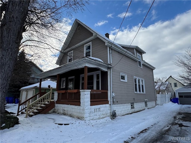 snow covered property featuring a garage and covered porch