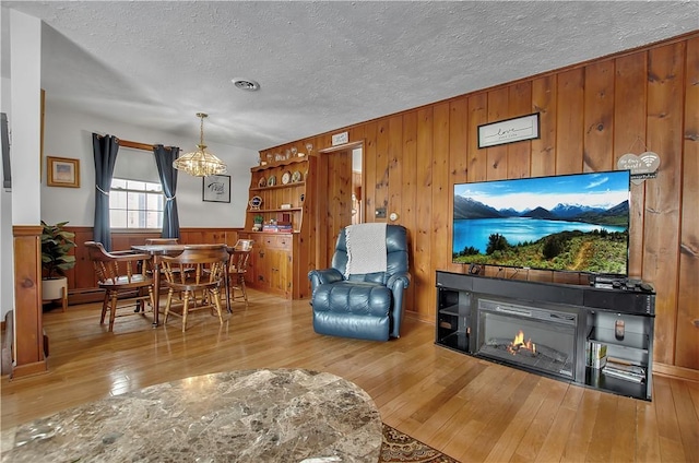 living room featuring wood walls, light hardwood / wood-style flooring, and a textured ceiling