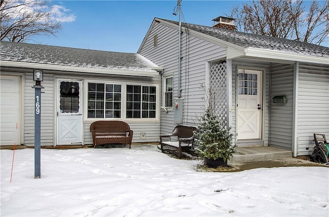 snow covered property entrance with a garage