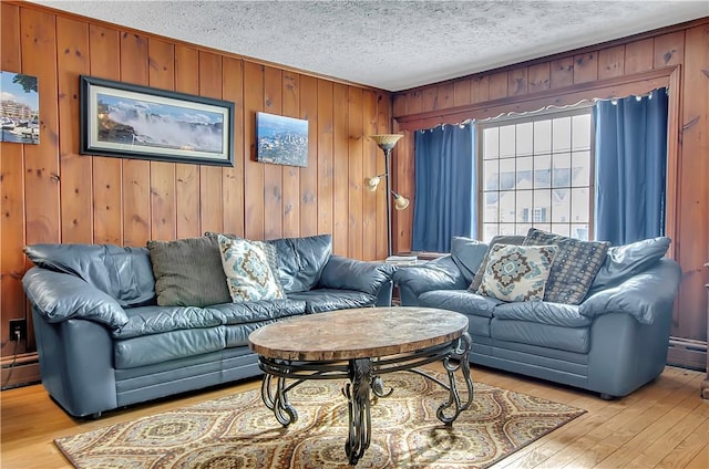 living room featuring wood walls, a textured ceiling, light hardwood / wood-style floors, and baseboard heating