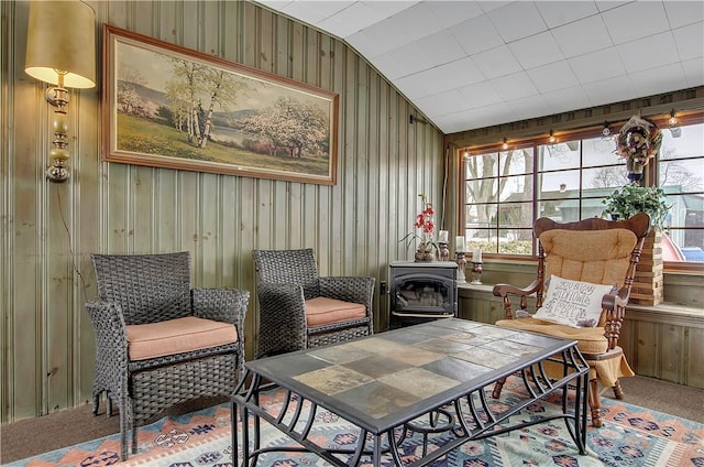 living area with carpet flooring, vaulted ceiling, and a wood stove