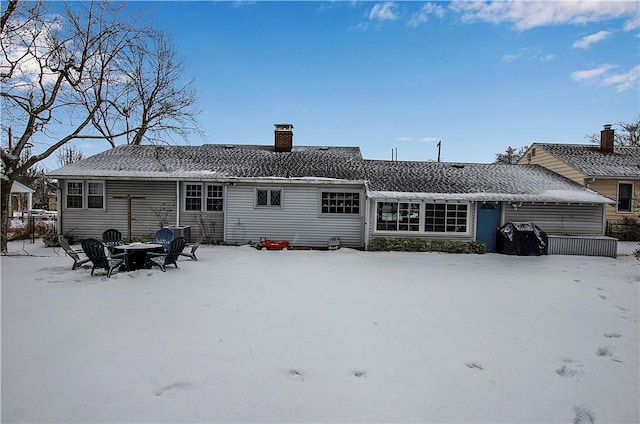 snow covered rear of property with a fire pit