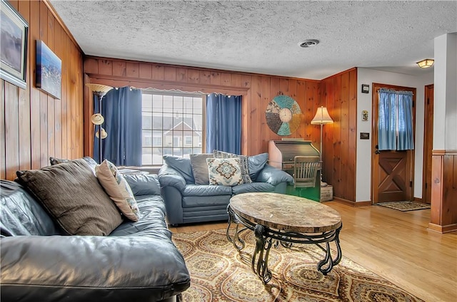 living room with wooden walls, light hardwood / wood-style floors, and a textured ceiling