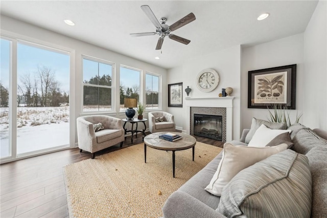 living room with a tiled fireplace, hardwood / wood-style flooring, and ceiling fan