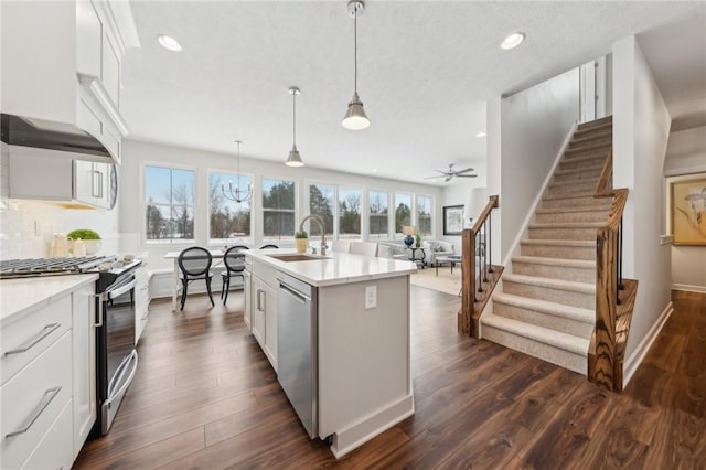 kitchen featuring white cabinetry, a kitchen island with sink, sink, and decorative light fixtures