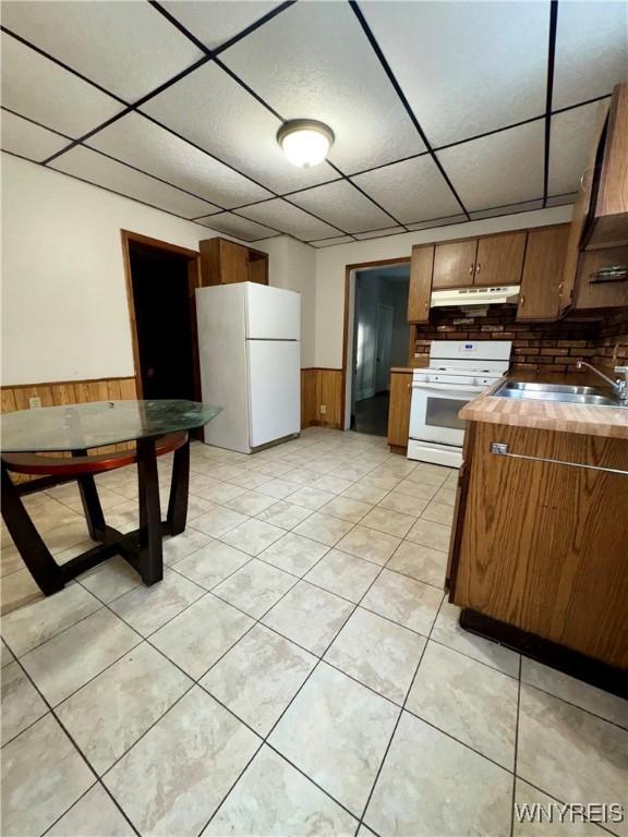 kitchen featuring sink, white appliances, a paneled ceiling, and light tile patterned flooring