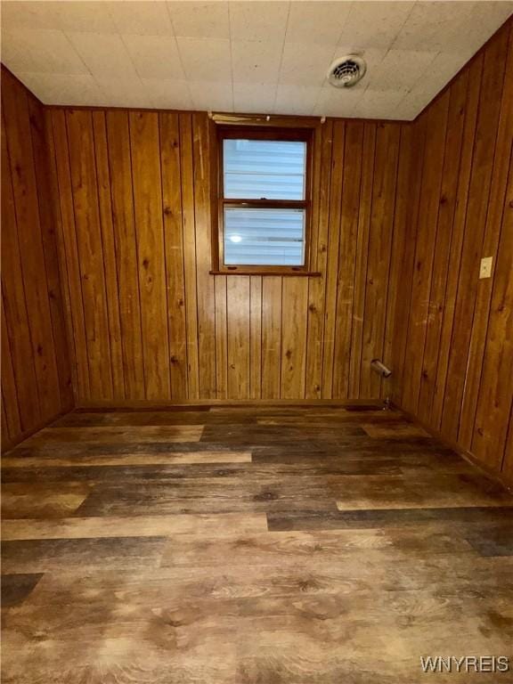 spare room featuring dark hardwood / wood-style floors and wood walls