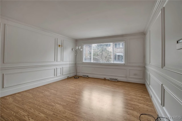 unfurnished room featuring ornamental molding and light hardwood / wood-style floors