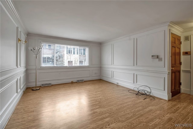 empty room featuring crown molding and light wood-type flooring