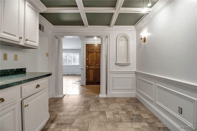 interior space featuring coffered ceiling, ornate columns, ornamental molding, beamed ceiling, and white cabinets