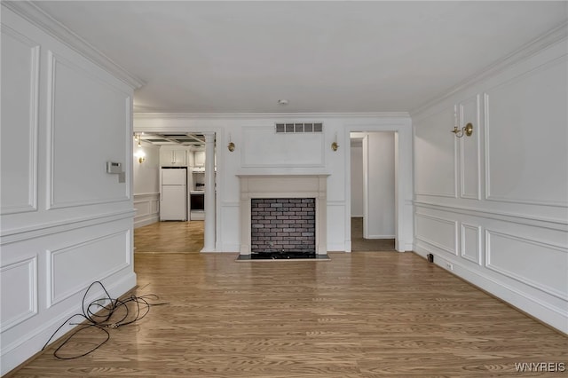 unfurnished living room featuring ornamental molding and light wood-type flooring