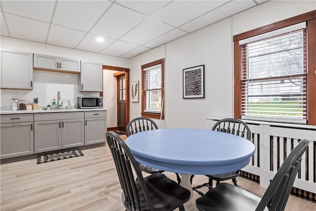 dining space with sink, a paneled ceiling, and light hardwood / wood-style floors