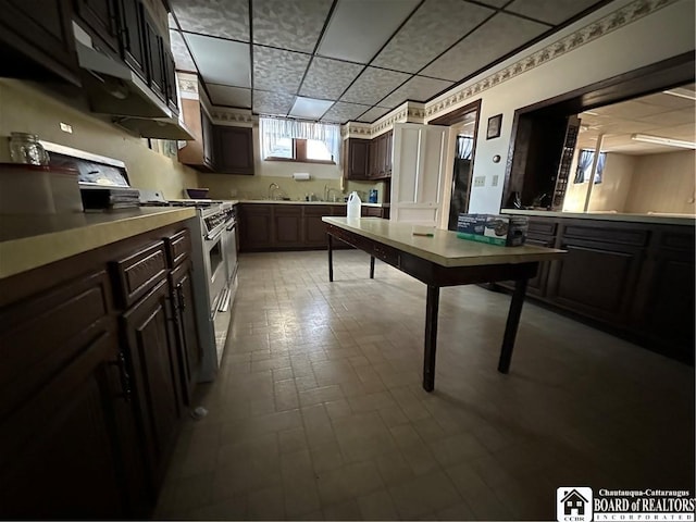 kitchen with a drop ceiling, dark brown cabinetry, and high end stainless steel range oven