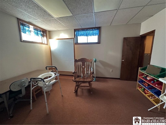 living area with a drop ceiling, plenty of natural light, and carpet flooring