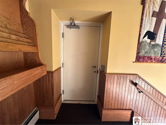 interior space with a baseboard radiator and wooden walls