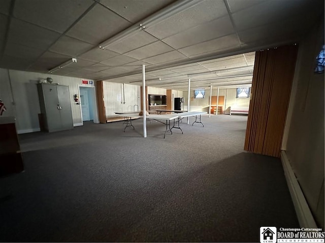 basement with carpet floors, a paneled ceiling, and baseboard heating