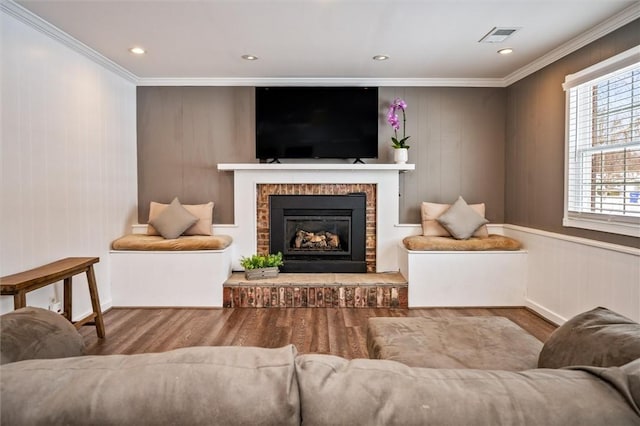 living room featuring crown molding, a fireplace, and light wood-type flooring