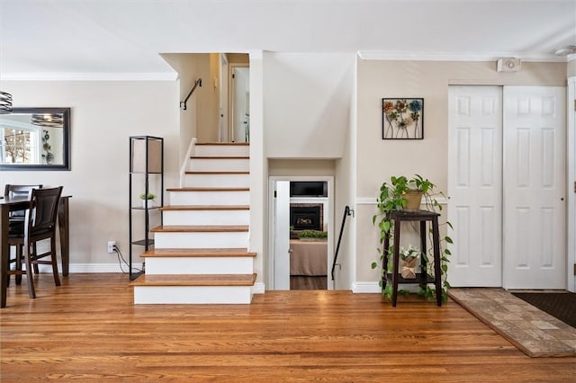 foyer entrance with hardwood / wood-style floors, crown molding, and a brick fireplace