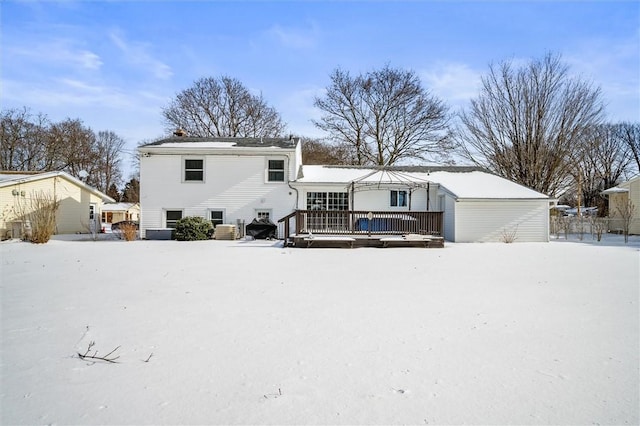 snow covered rear of property with a deck