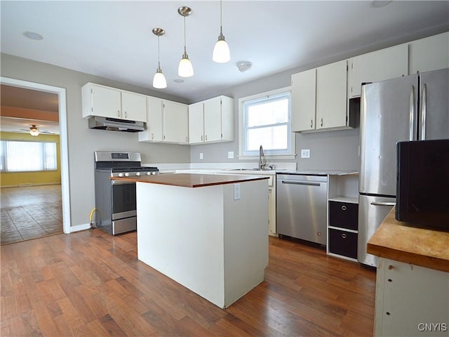 kitchen with stainless steel appliances, a kitchen island, pendant lighting, and white cabinets