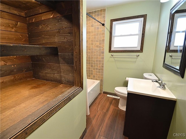 full bathroom with vanity, hardwood / wood-style flooring, tiled shower / bath combo, and toilet