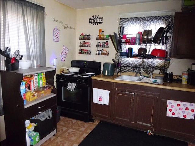 kitchen featuring light parquet flooring, dark brown cabinets, sink, and black gas range