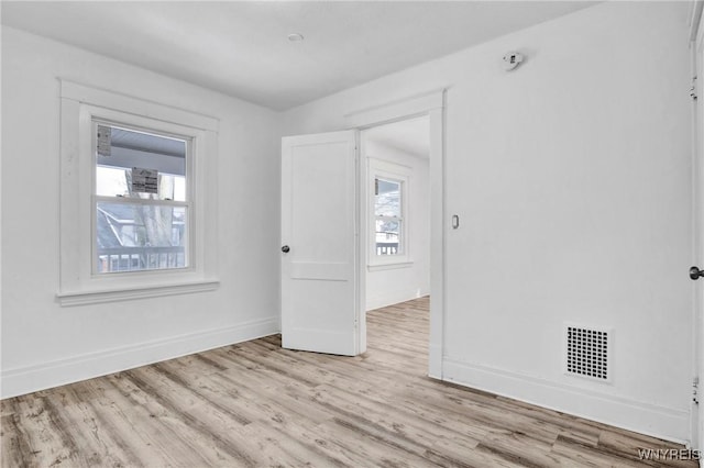 empty room with a wealth of natural light and light wood-type flooring