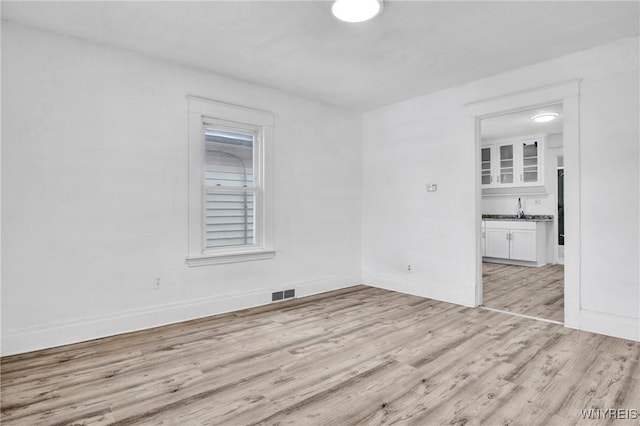 spare room with sink and light hardwood / wood-style flooring