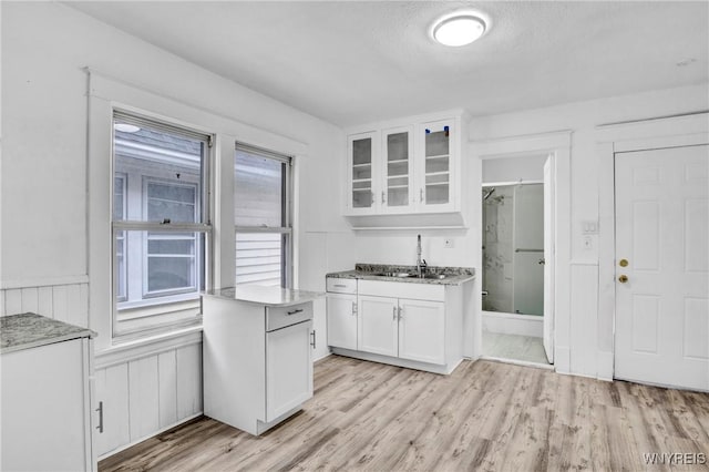 kitchen with sink, white cabinets, and light wood-type flooring