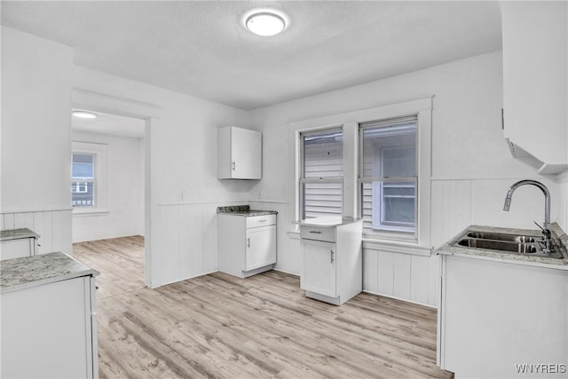 kitchen featuring white cabinetry, sink, a textured ceiling, and light hardwood / wood-style floors