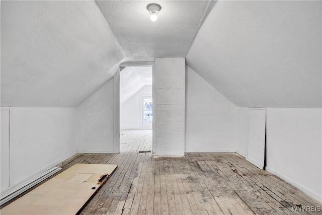 bonus room featuring lofted ceiling, a textured ceiling, and light hardwood / wood-style flooring