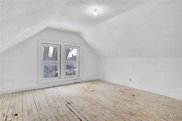 bonus room with lofted ceiling, a textured ceiling, and light wood-type flooring