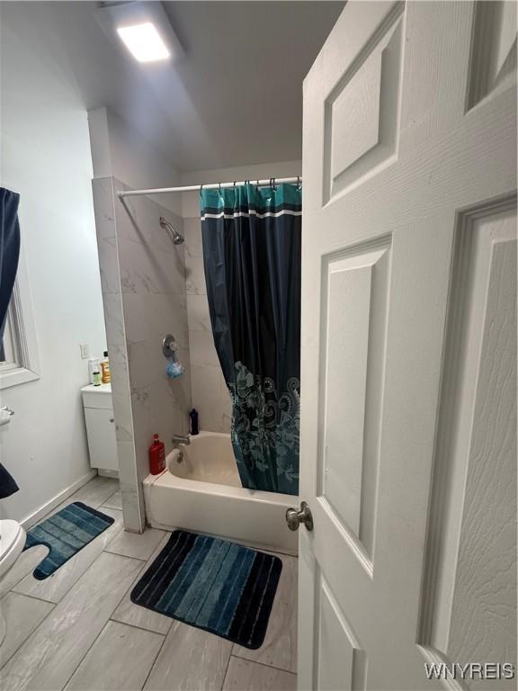 bathroom with shower / bath combination with curtain and toilet