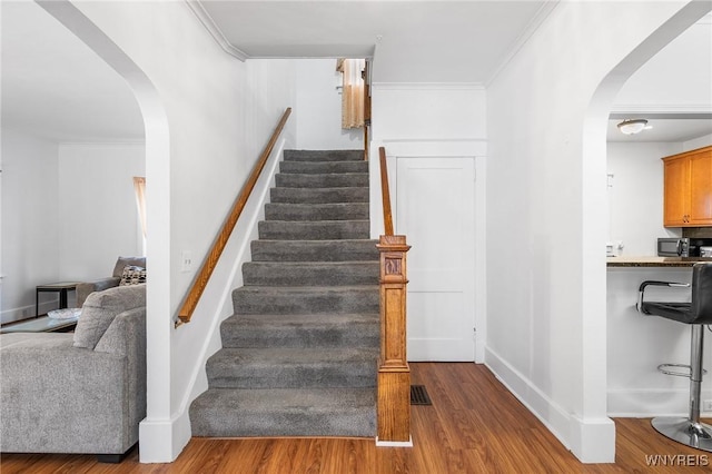 stairs featuring crown molding and wood-type flooring