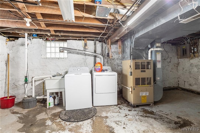 basement featuring sink, heating unit, washing machine and clothes dryer, and electric panel