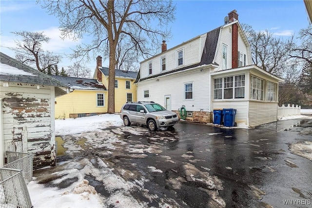 snow covered rear of property with a sunroom