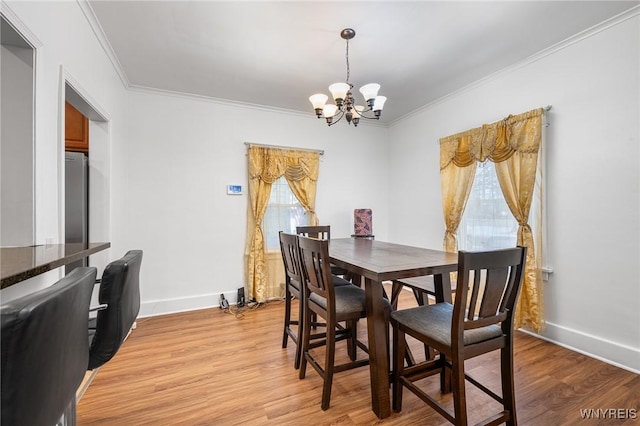 dining room featuring crown molding, an inviting chandelier, and light wood-type flooring