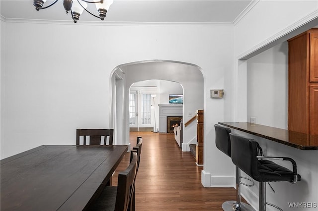 dining space with dark wood-type flooring, ornamental molding, and a chandelier