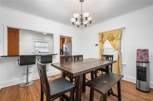 dining space with an inviting chandelier, crown molding, and light wood-type flooring