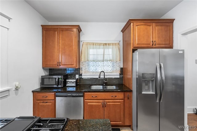 kitchen featuring appliances with stainless steel finishes, sink, decorative backsplash, and dark stone countertops