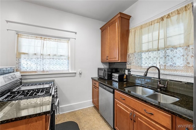 kitchen featuring dark stone countertops, sink, tasteful backsplash, and appliances with stainless steel finishes